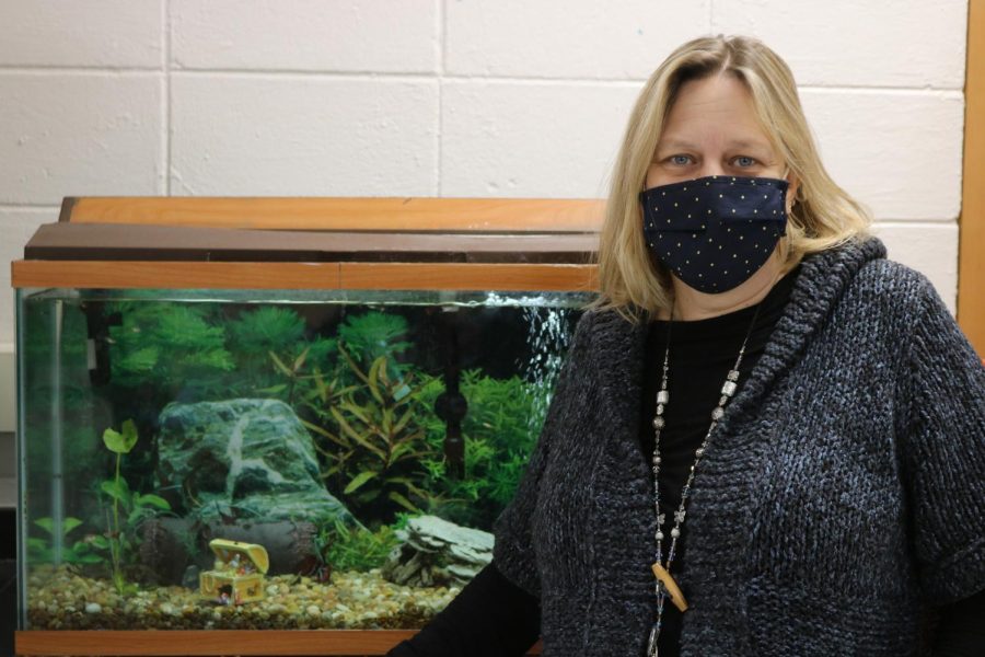 Mrs. Hannan standing beside her class fish tank.
