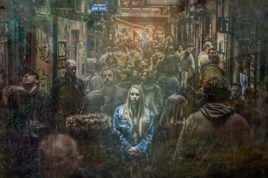 Woman standing in the crowd, is symbolic of feeling alone in a room full of people.